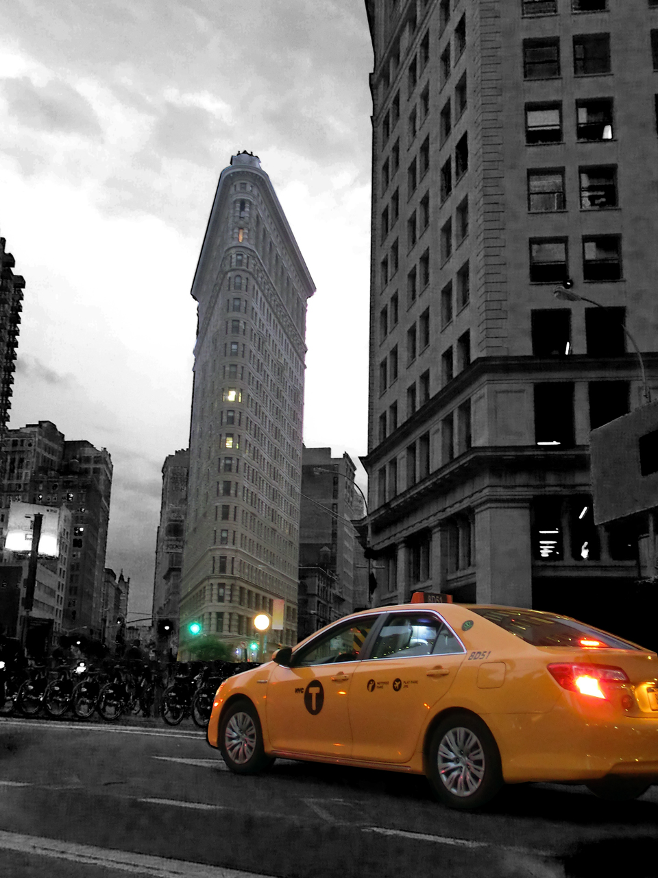 Flatiron Building mit gelbem NYC Taxi - in schwarz-weißer Umgebung
