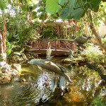 Teich mit Skulpturen und einer Holzbrücke im Hotel-Innenhof