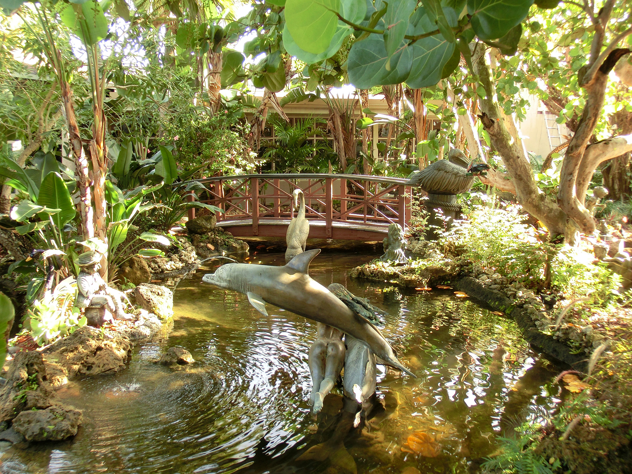 Teich mit Skulpturen und einer Holzbrücke im Hotel-Innenhof