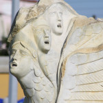 Skulptur an der Hafenpromenade mit drei schreinden Gesichtern